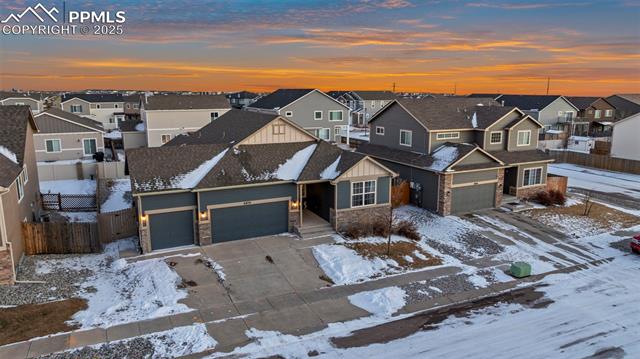 6854 Red Cardinal Loop Colorado Springs, CO 80908 - Photo 4 of 37 Aerial view of house featuring a three-car garage at dusk