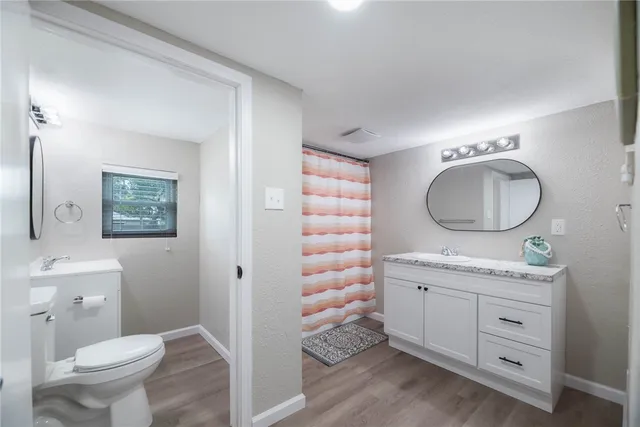 a bathroom with a toilet a sink a mirror and a window