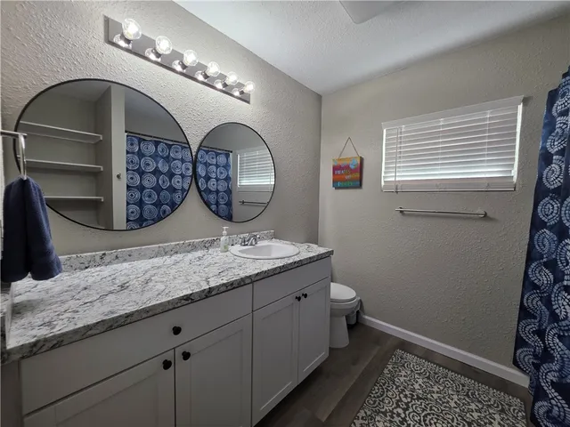 a bathroom with a granite countertop toilet a sink and a mirror