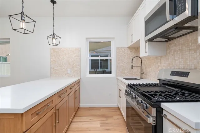 a kitchen that has a sink stainless steel appliances granite counter tops and a wooden floors