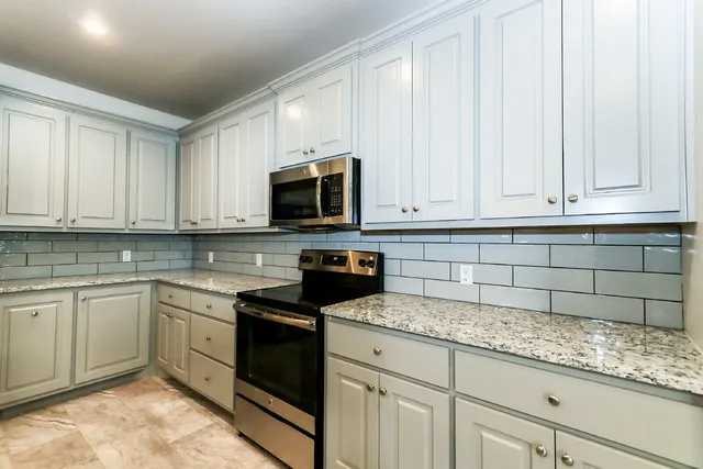 a kitchen with granite countertop white cabinets and stainless steel appliances