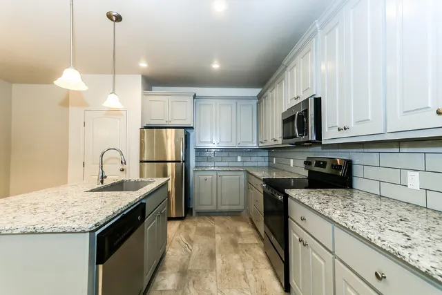 a kitchen with kitchen island granite countertop a sink a counter top space stainless steel appliances and cabinets
