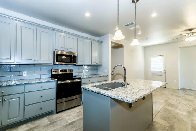 a kitchen with kitchen island granite countertop stainless steel appliances sink microwave and stove