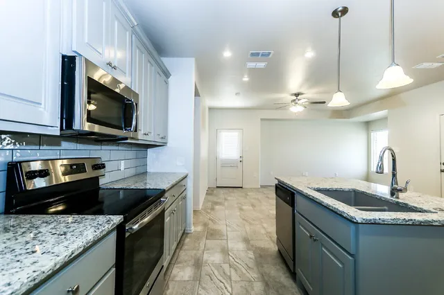 a kitchen with stainless steel appliances granite countertop a sink a stove and a microwave