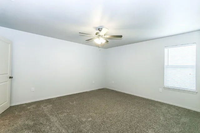 an empty room with windows and chandelier fan