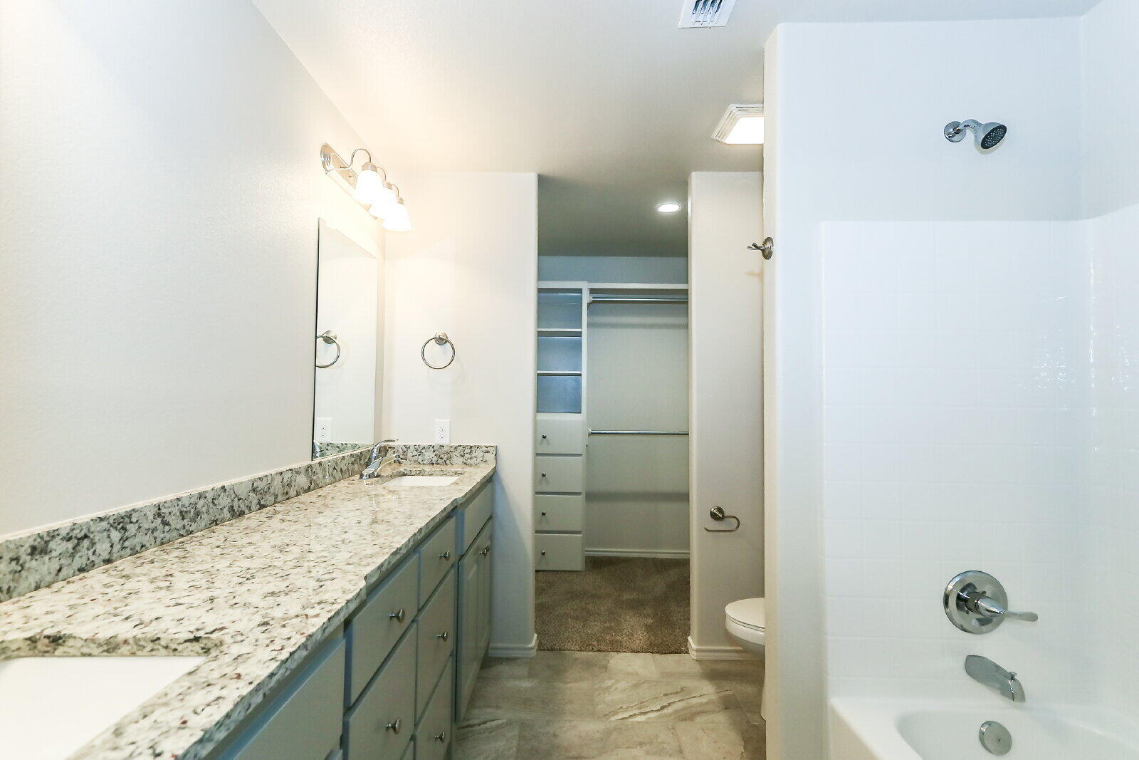 6905 67th Street, Unit B Lubbock, TX 79424 - Photo 23 of 37 a bathroom with a granite countertop sink and mirror with bathtub