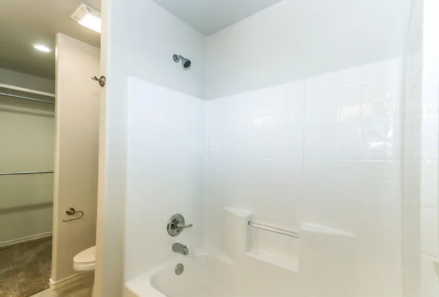 a bathroom with a bathtub shower sink vanity and toilet