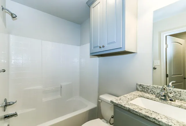 a bathroom with a granite countertop bathtub sink vanity and toilet