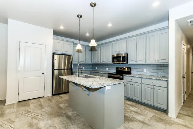 a kitchen with stainless steel appliances granite countertop a refrigerator a sink dishwasher a stove and white cabinets with wooden floor