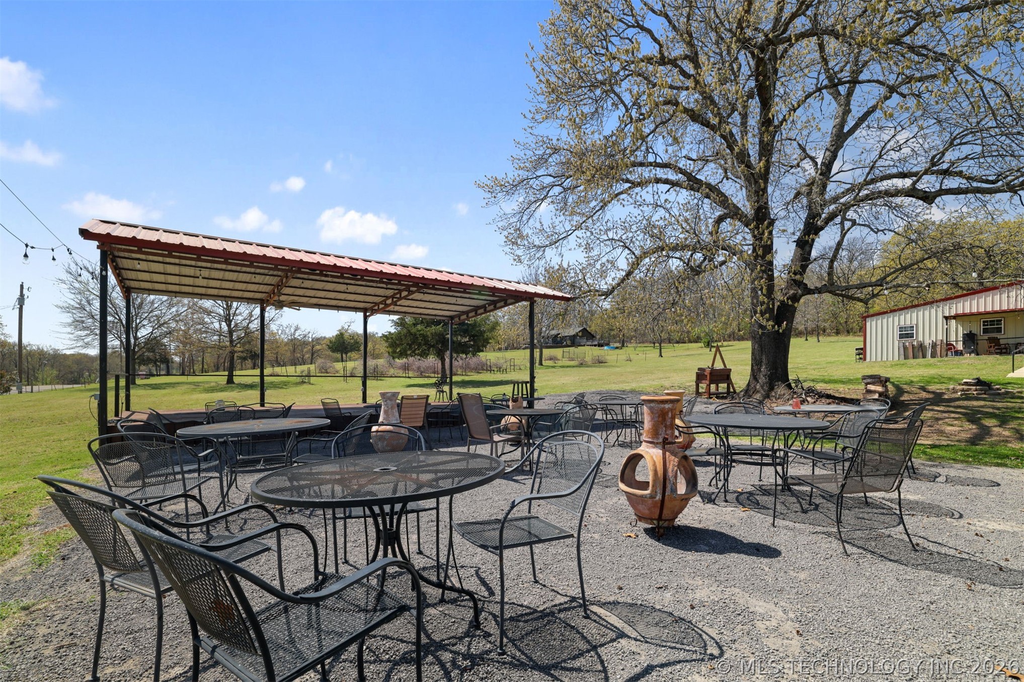 3565 Sawmill Road Caddo, OK 74729 - Photo 22 of 32 Expansive outdoor patio area featuring a covered structure, gravel surfacing, and mature trees