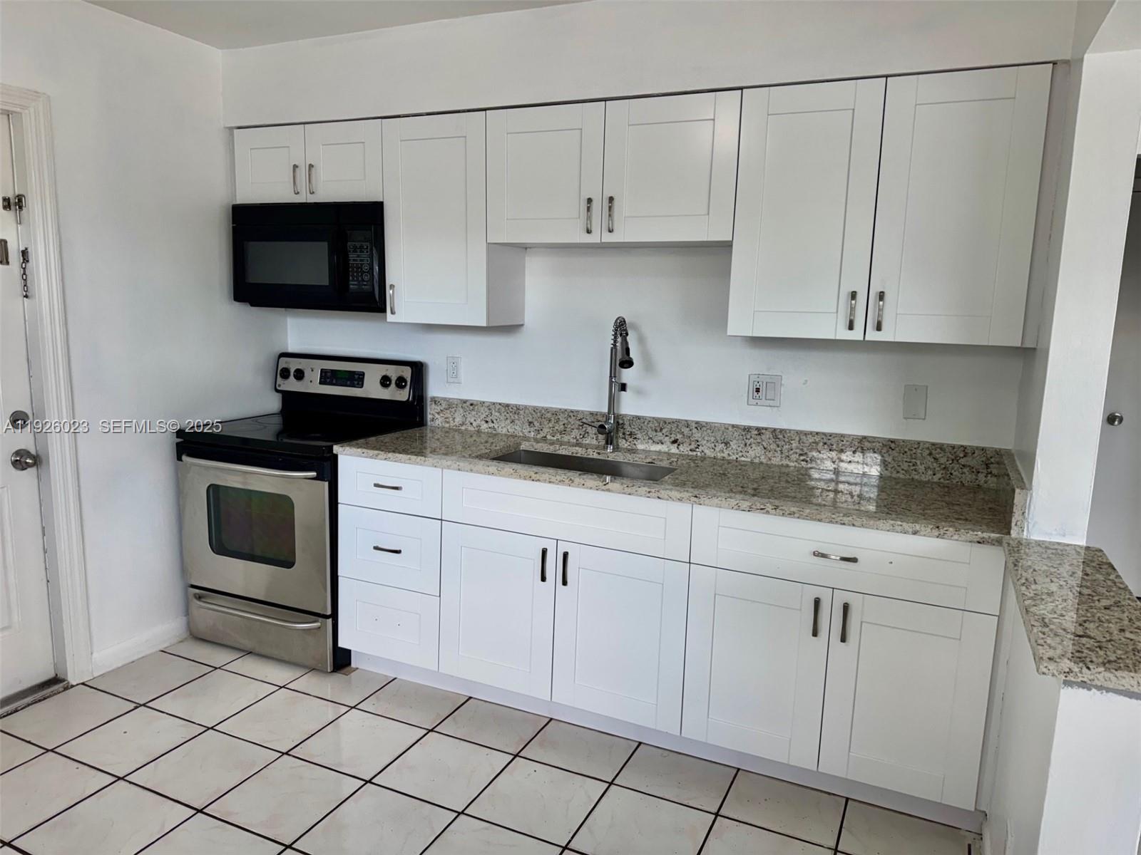 718 Southwest 7th Street, Unit 718 Hallandale Beach, FL 33009 - Photo 2 of 13 a kitchen with white cabinets and black appliances