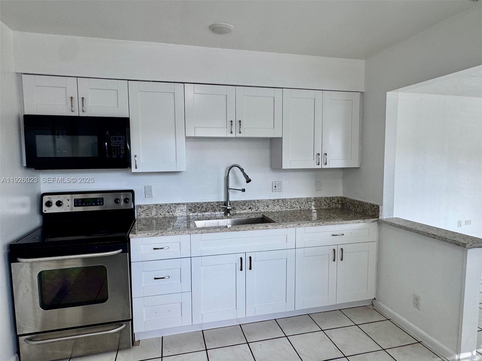 718 Southwest 7th Street, Unit 718 Hallandale Beach, FL 33009 - Photo 3 of 13 a kitchen with appliances a sink and cabinets