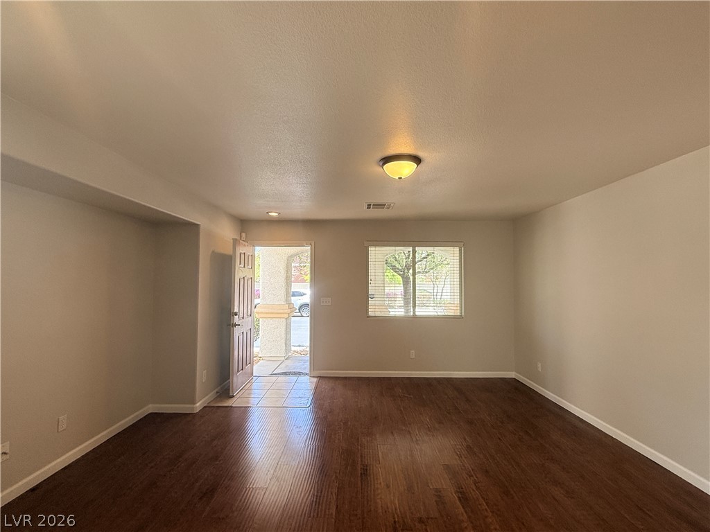 11953 Fairfax Ridge Street Las Vegas, NV 89183 - Photo 4 of 32 Rich hardwood-style flooring extends from the inviting entryway into a bright, versatile living area.