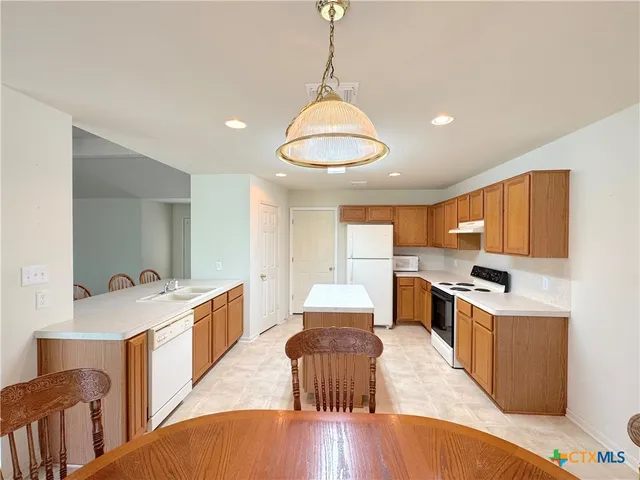 a kitchen with a stove a refrigerator and a dining table