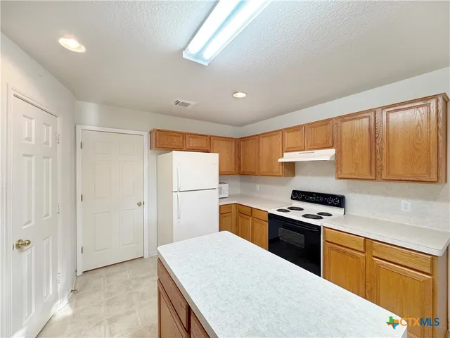 a kitchen with a sink a stove cabinets and a refrigerator