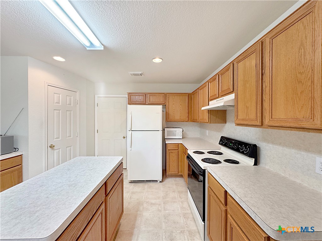 4575 Tanglewood Trail Spring Branch, TX 78070 - Photo 18 of 48 a kitchen with a sink a stove cabinets and a refrigerator