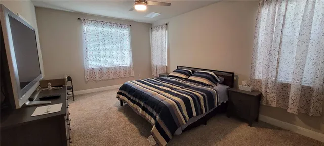 a bedroom with a bed and a flat tv screen on a dresser