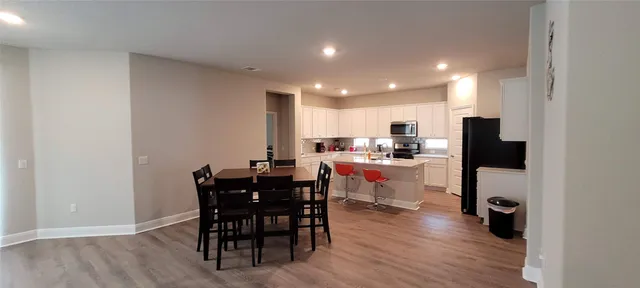 a kitchen with a dining table chairs and wooden floor