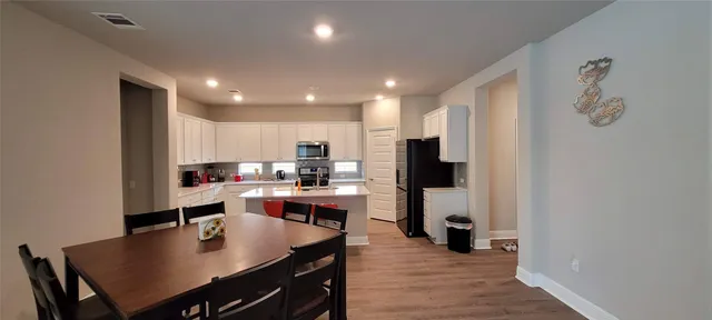 a kitchen with a dining table chairs and refrigerator
