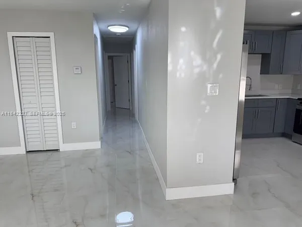 a view of an empty room with kitchen and a window