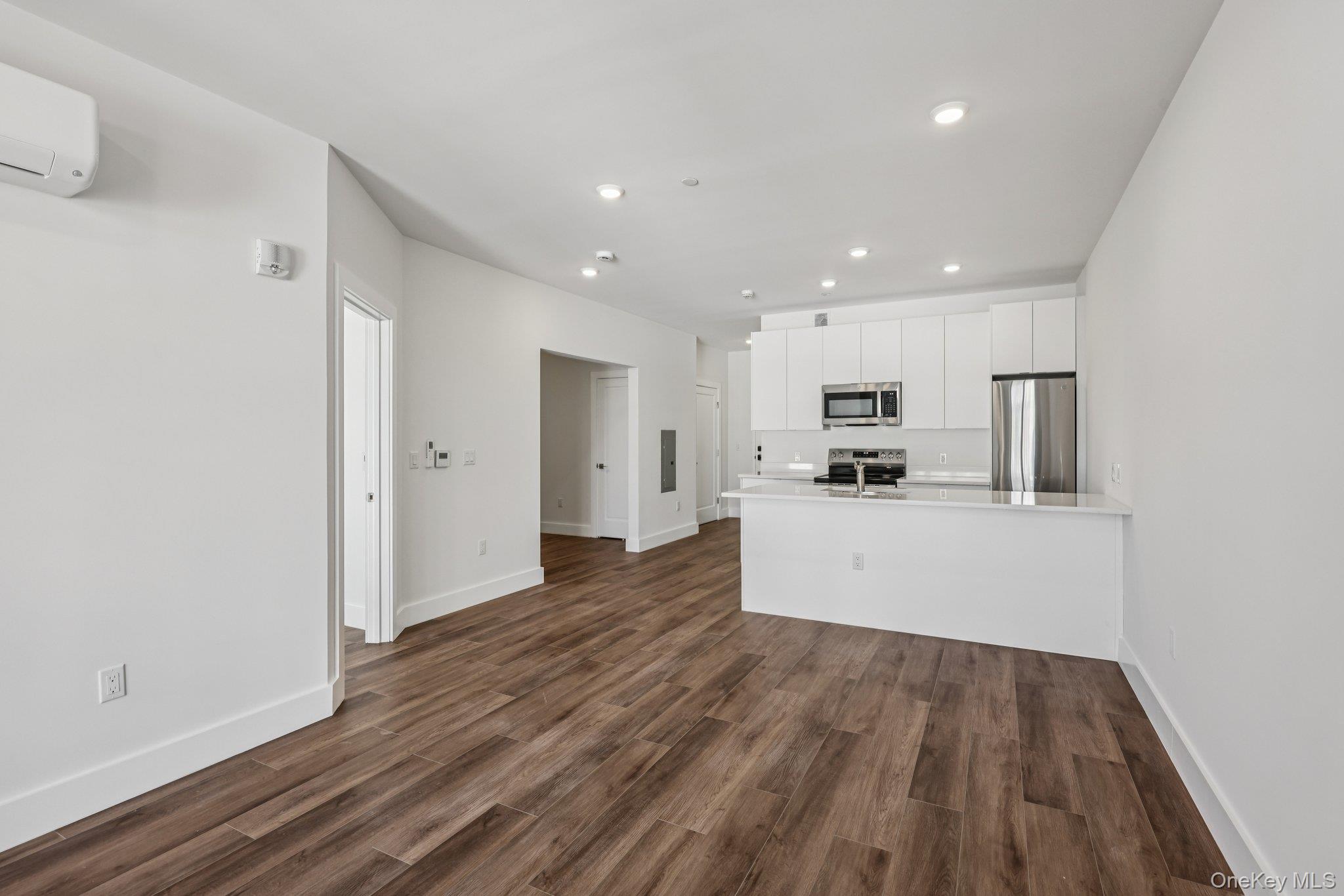 199 East Post Road, Unit 202 White Plains, NY 10601 - Photo 13 of 21 a view of a kitchen with cabinets stainless steel appliances wooden floor and a window