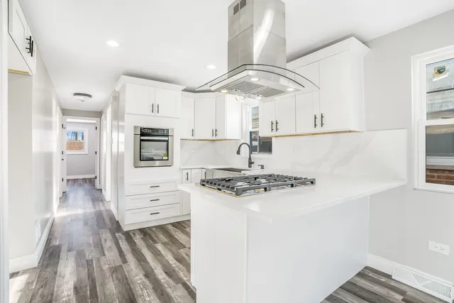 a kitchen with stainless steel appliances a stove a sink and white cabinets