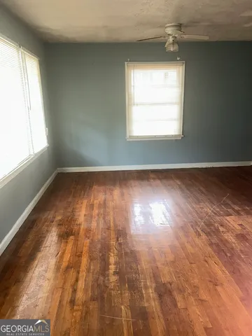 an empty room with wooden floor and windows