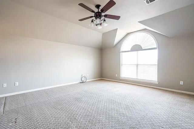 an empty room with chandelier fan and windows