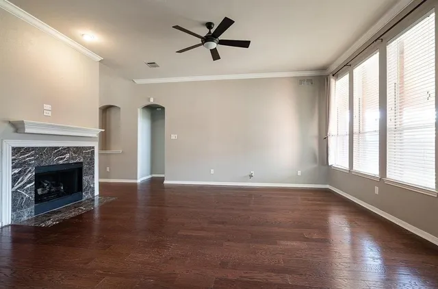 an empty room with wooden floor fireplace and windows