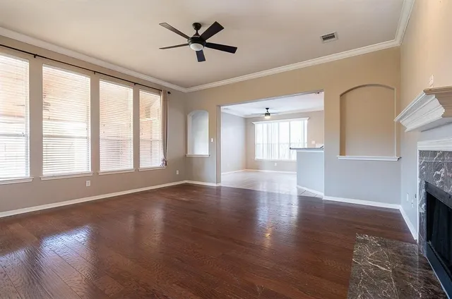 a view of an empty room with a window and wooden floor