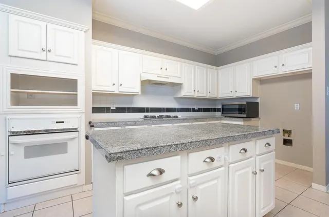 a kitchen with granite countertop white cabinets and white appliances