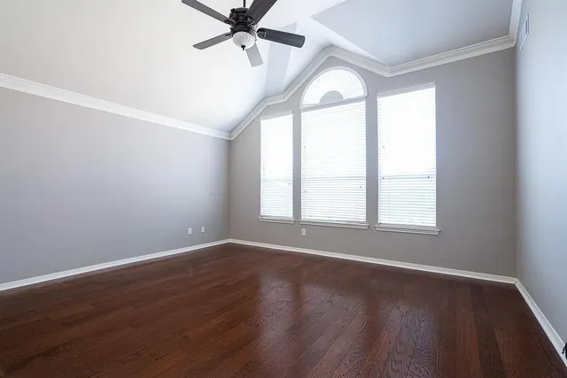 an empty room with wooden floor fan and windows