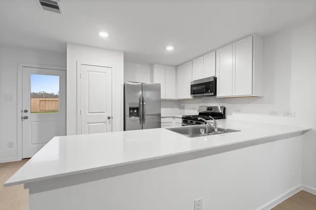 a kitchen with a refrigerator a microwave a sink and cabinets
