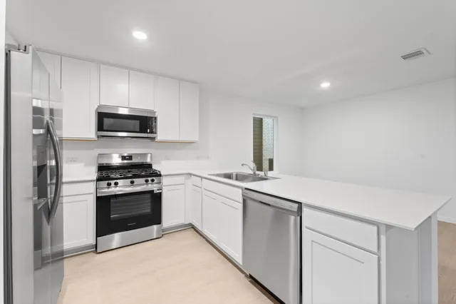 a kitchen with stainless steel appliances a stove a sink and a microwave