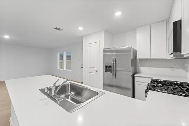 a kitchen with stainless steel appliances granite countertop a sink a refrigerator and a stove