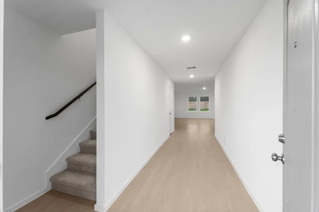 a view of a hallway with wooden floor and staircase