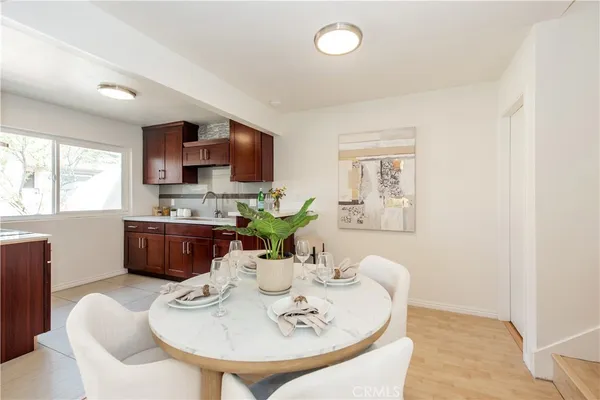a living room with stainless steel appliances furniture a dining table and a window