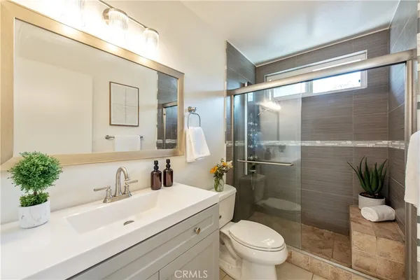 a bathroom with a sink a toilet a glass door a shower and a mirror