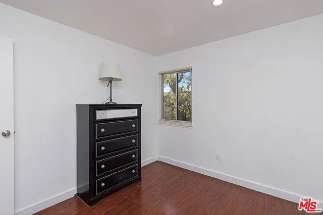 an empty room with a dresser and a window