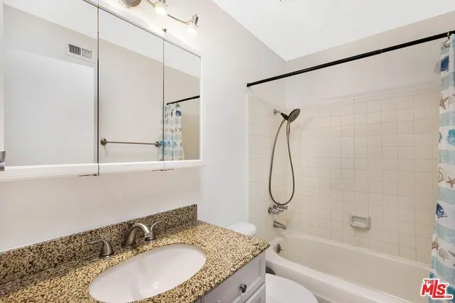 a bathroom with a granite countertop sink a toilet and shower
