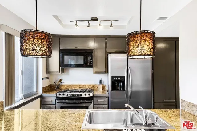 a kitchen with stainless steel appliances granite countertop a refrigerator and a stove top oven