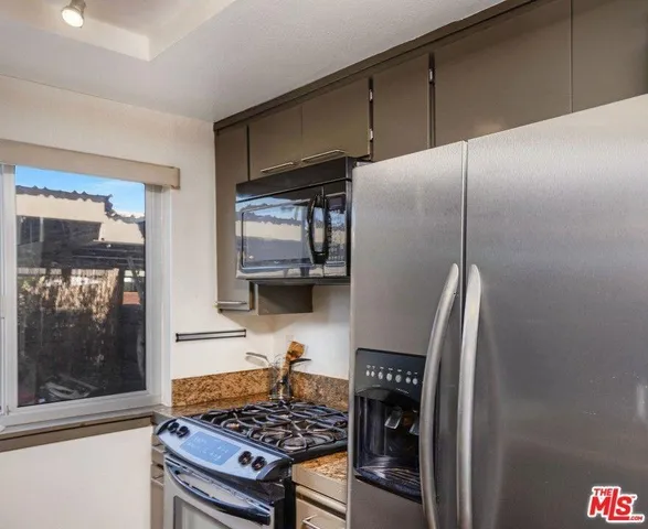 a kitchen with stainless steel appliances granite countertop a refrigerator and a stove top oven