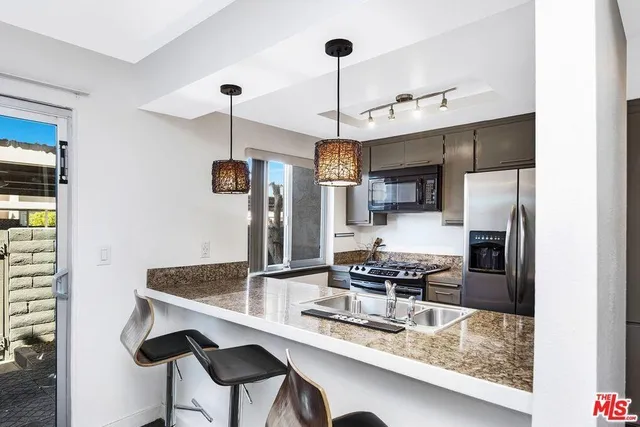 a kitchen with stainless steel appliances granite countertop a sink refrigerator and cabinets