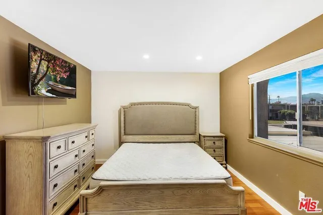 a room with a bed and a flat tv screen on the dresser