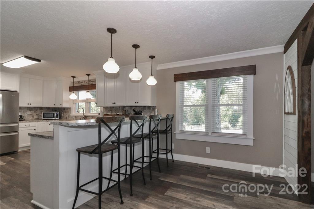 147 Stack Road Olin, NC 28660 - Photo 11 of 47 a kitchen with stainless steel appliances granite countertop a stove top oven a sink dishwasher and a dining table with wooden floor