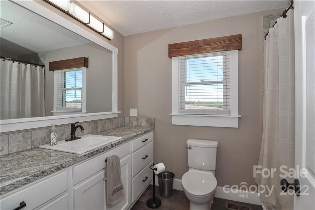147 Stack Road Olin, NC 28660 - Photo 19 of 47 a bathroom with a granite countertop toilet a sink a mirror and a window