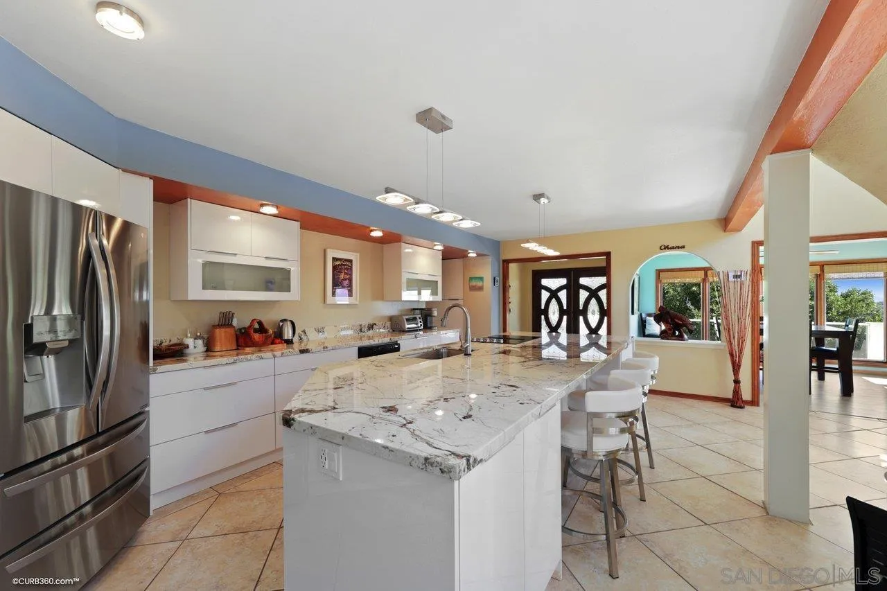 1778 Kings Road Vista, CA 92084 - Photo 22 of 49 a kitchen with a sink a refrigerator and chairs