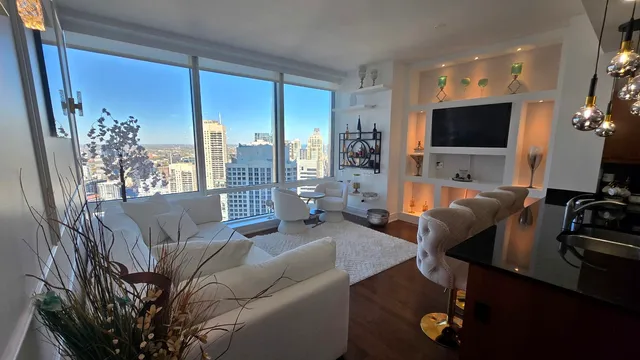 a living room with furniture floor to ceiling window and a flat screen tv
