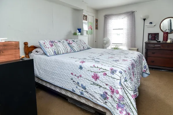 a bedroom with a bed and dresser with mirror