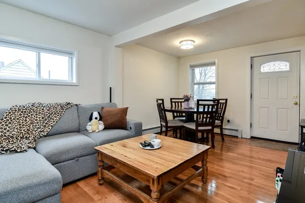 a living room with furniture a wooden floor and next to a window